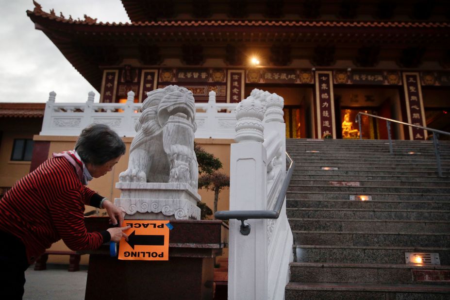 Volunteer Fu Hua Chen puts up a sign near a polling place at the Hsi Lai Temple in Hacienda Heights, California.
