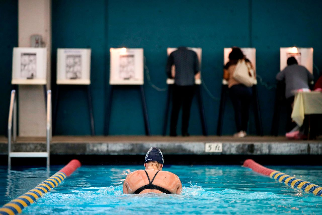 Sarah Salem swims at the Echo Deep Pool in Los Angeles as voters cast their ballots nearby.