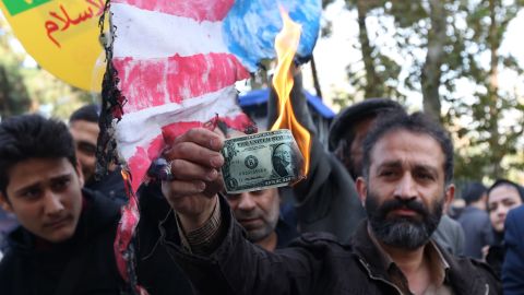 An Iranian protester burns a dollar bill during a demonstration outside the former US embassy in the Iranian capital of Tehran on November 4, 2018.