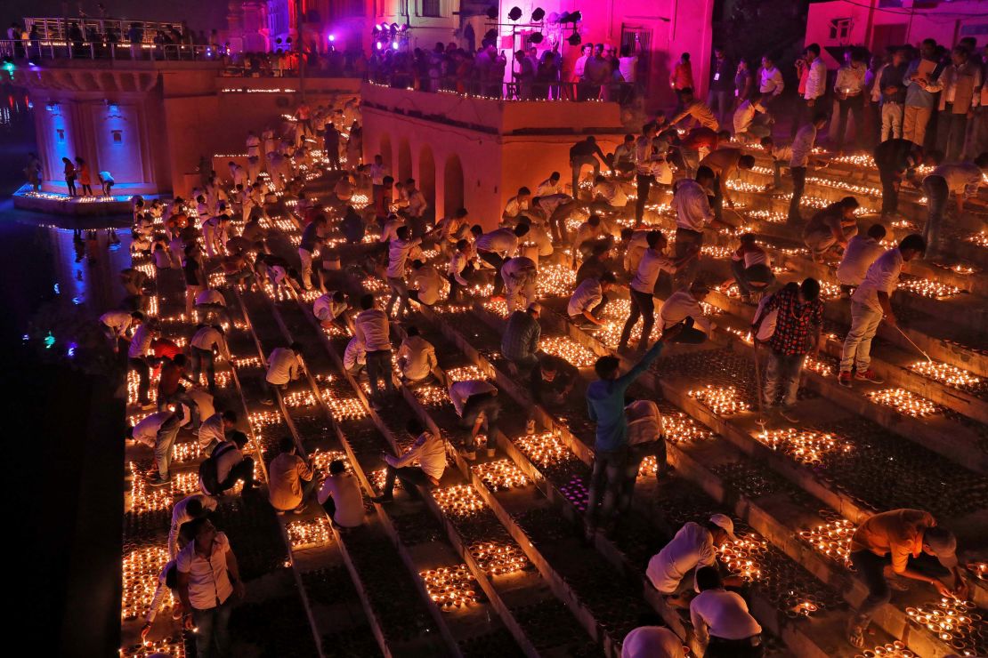 Participants light earthen oil lamps on the banks of the Sarayu river in an attempt to enter the Guinness World Records for the largest display of oil lamps on the eve of Diwali
