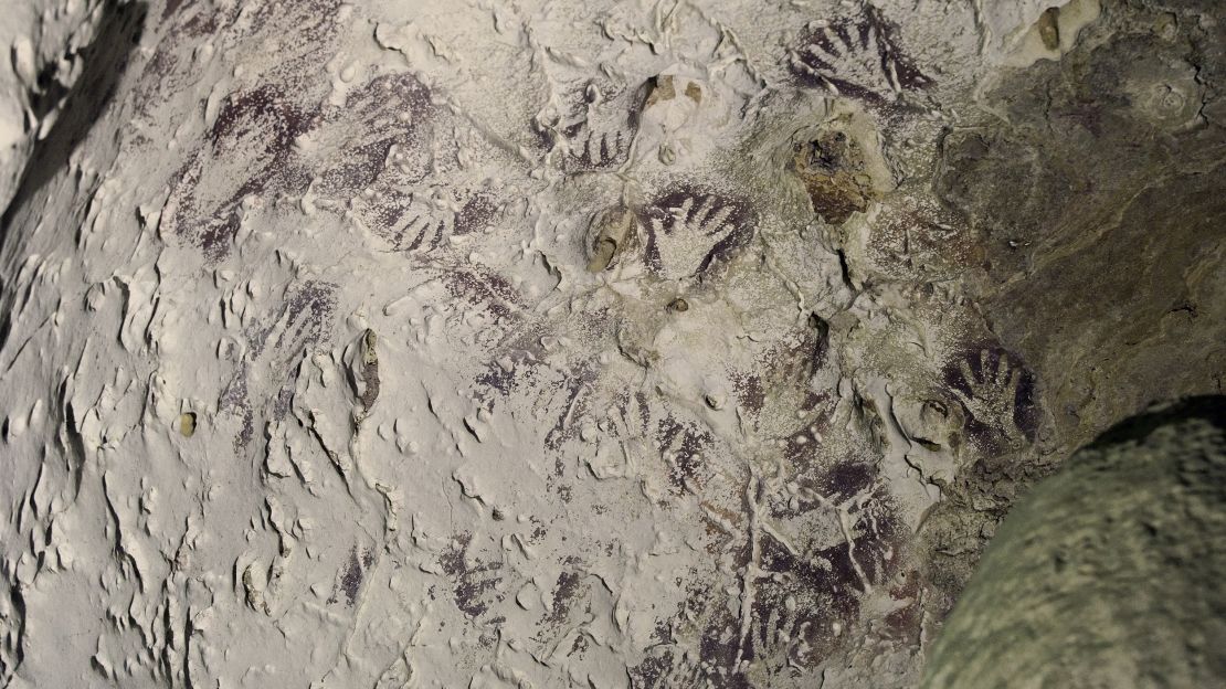 Composition of mulberry-colored hand stencils from 20,000 years ago.