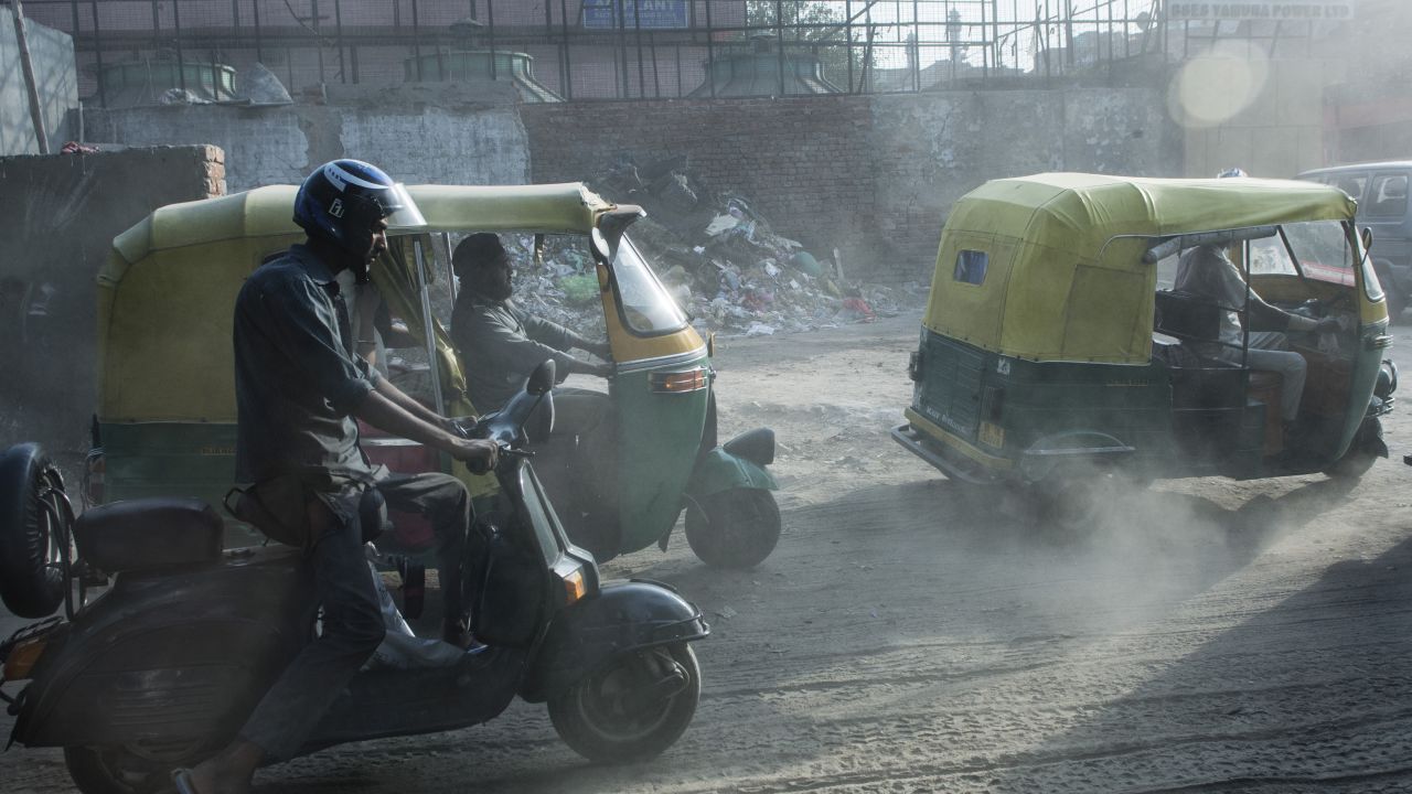 Auto rickshaw drivers pass a building site in Old Delhi.