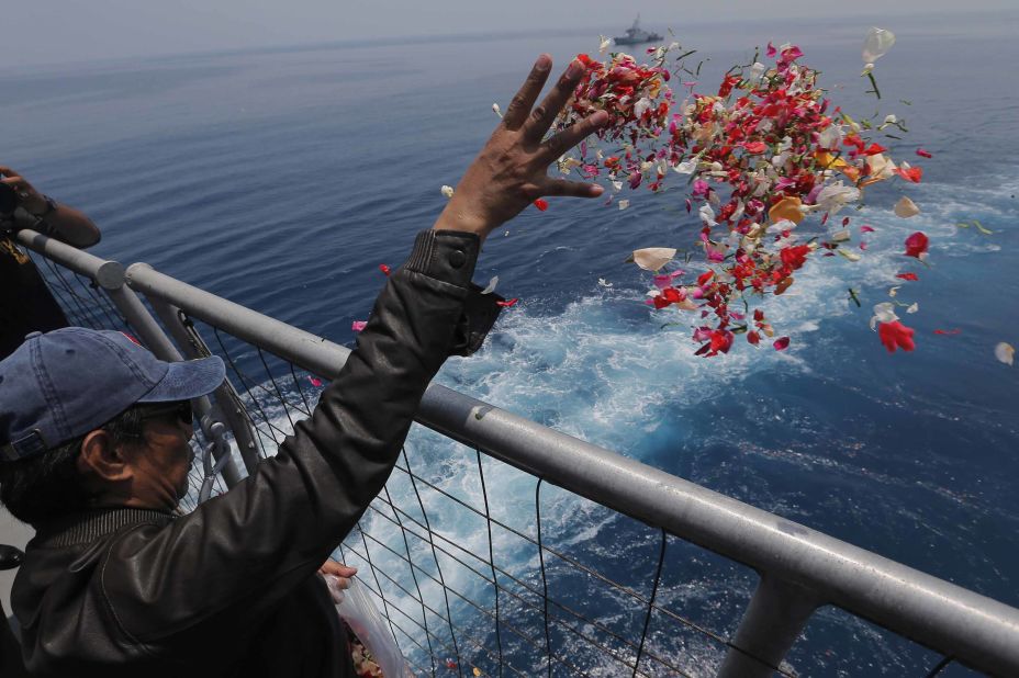 A relative of one of the crash victims tosses flower petals from an Indonesian Navy ship on Tuesday, November 6.