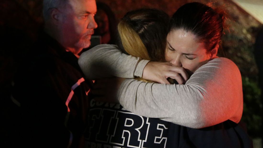 A woman who fled from the shooting gets hugs from relatives in Thousand Oaks.