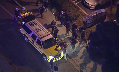 Officers stand near a police SUV at the shooting scene in an image from aerial video.