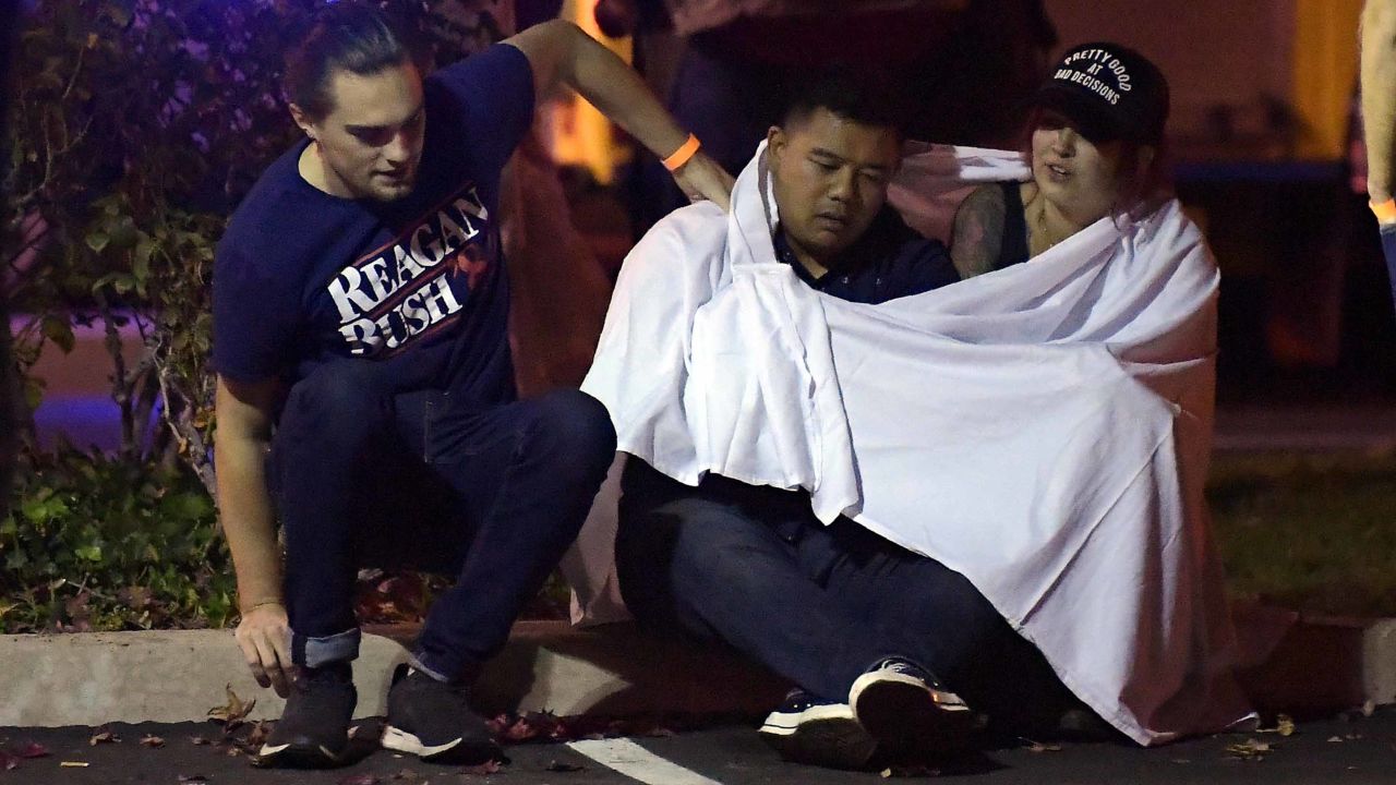 People comfort each other as they sit near the scene Thursday, Nov. 8, 2018, in Thousand Oaks, Calif. where a gunman opened fire Wednesday inside a country dance bar crowded with hundreds of people on "college night," wounding 11 people including a deputy who rushed to the scene. Ventura County sheriff's spokesman says gunman is dead inside the bar. (AP Photo/Mark J. Terrill)
