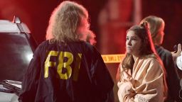 An FBI agent talks to a potential witness as they stand near the scene Thursday, Nov. 8, 2018, in Thousand Oaks, Calif. where a gunman opened fire Wednesday inside a country dance bar crowded with hundreds of people on "college night," wounding 11 people including a deputy who rushed to the scene. Ventura County sheriff's spokesman says gunman is dead inside the bar. (AP Photo/Mark J. Terrill)