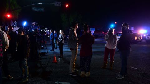 People watch as police vehicles close off the area outside a country music bar and dance hall in Thousand Oaks.