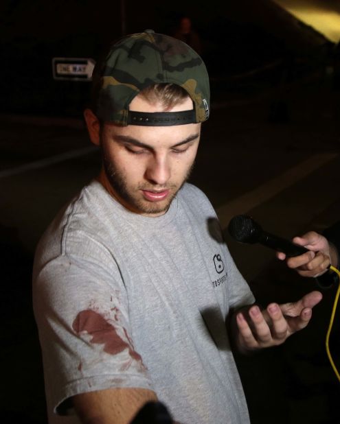 Matt Wennerstorm, still wearing a blood-stained shirt, talks to members of the media outside the Borderline Bar & Grill.