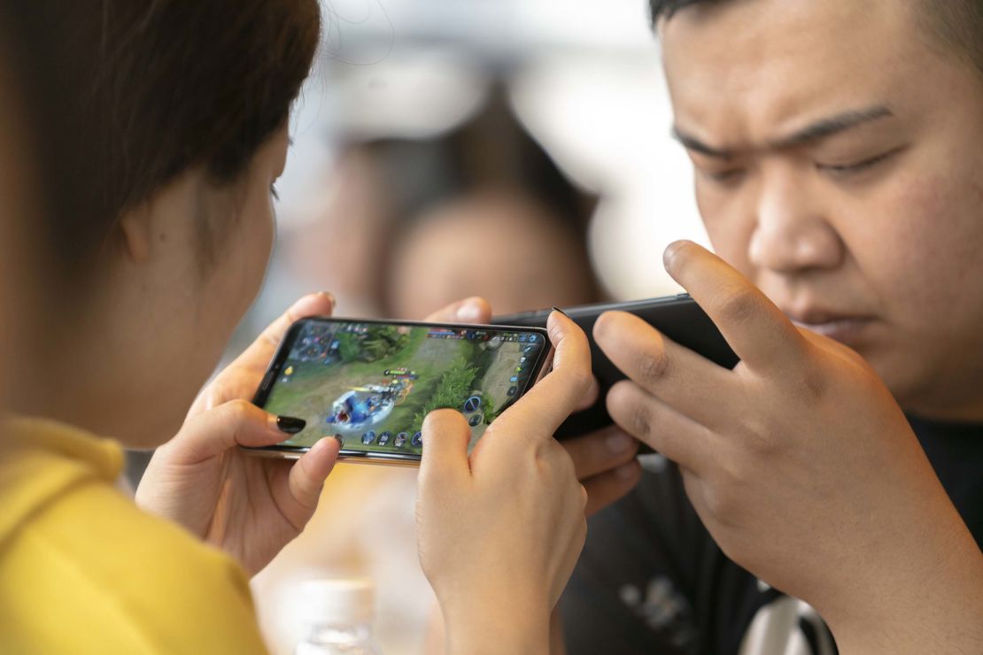 Young people play video games on mobile phones in a cafe. 