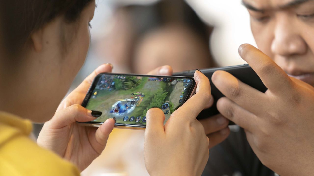 Young people play video games on mobile phones in a cafe.