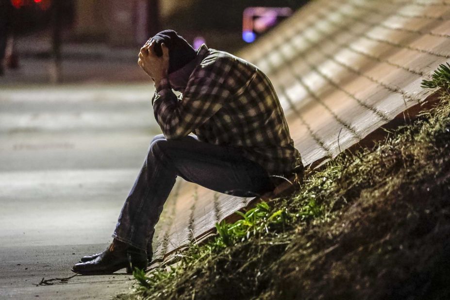 Tim Dominguez, who was in the bar with his son, sits distraught under a freeway overpass near the crime scene in Thousand Oaks.