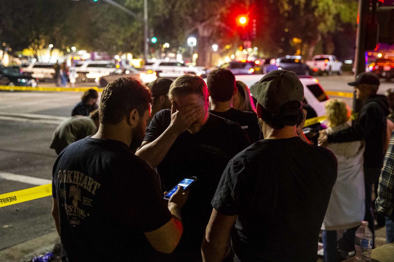People stand in a parking lot along South Moorpark Road in Thousand Oaks in the aftermath of the shooting.