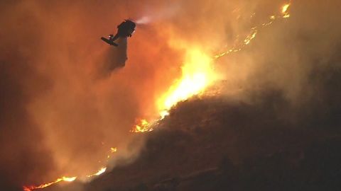 A helicopter sprays blazing wildfires in California.