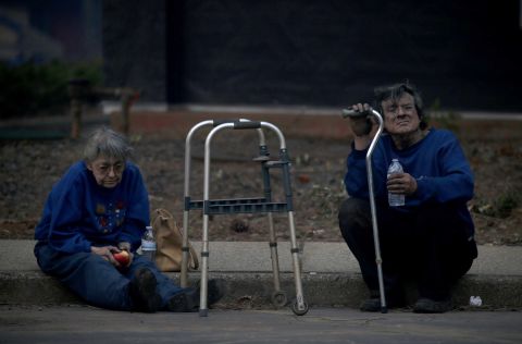 Juanita and Wayne McLish sit on a curb November 8 after losing their house to the Camp Fire in Paradise.