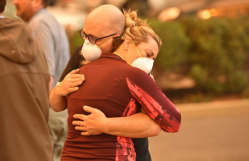 People embrace in the parking lot of a Paradise hospital as the Camp Fire engulfed it on November 8.