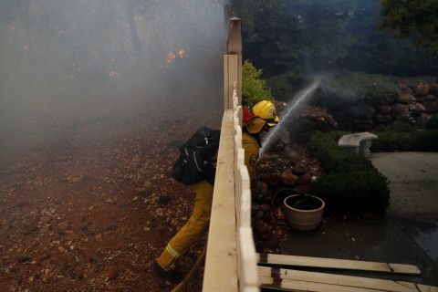 A firefighter works to extinguish a spot fire at a home in Paradise.