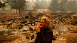 Cathy Fallon reacts as she stands near the charred remains of her home, Friday, Nov. 9, 2018, in Paradise, Calif. "I'll be darned if I'm going to let those horses burn in the fire," said Fallon, who stayed on her property to protect her 14 horses, all of which survived. (AP Photo/John Locher)