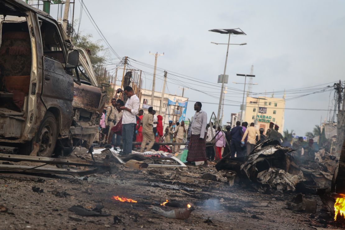 People gather in the street amid wreckage from car bombings in Mogadishu, Somalia.