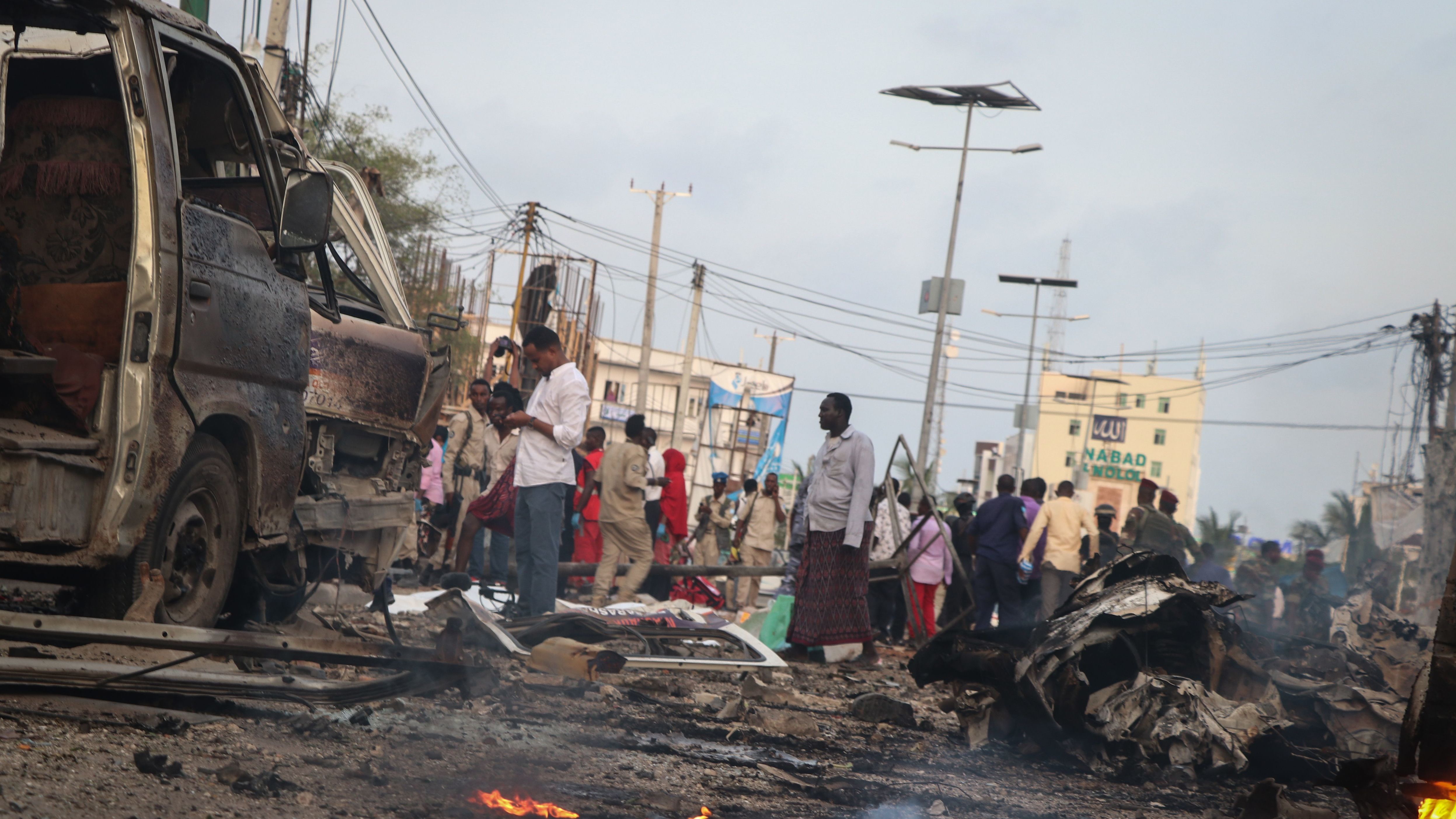People gather in the street amid wreckage from car bombings in Mogadishu, Somalia.