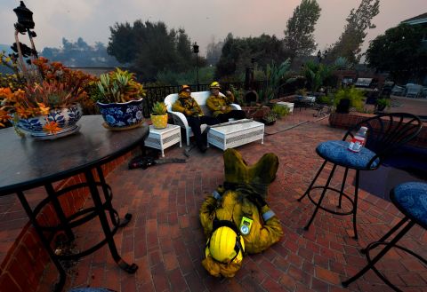 From left, firefighters Cory Darrigo, Omar Velasquez and Sam Quan rest in a Westlake Village backyard after battling the Woolsey Fire all night.