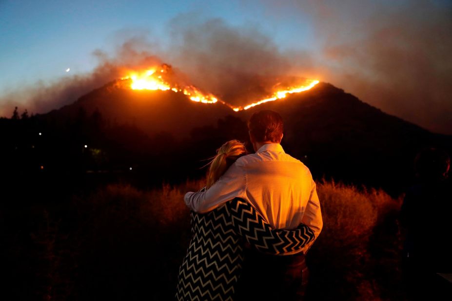 Roger Bloxberg and his wife, Anne, hug on Friday, November 9, as they watch a wildfire on a Los Angeles hilltop.