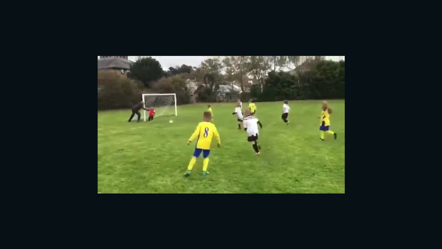A father was filmed nudging his son into the path of the ball during a football match in west Wales.