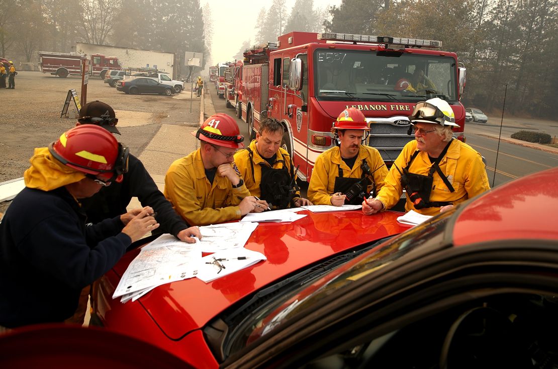 Firefighters hold a morning meeting as they battle the Camp Fire on Saturday in Paradise.