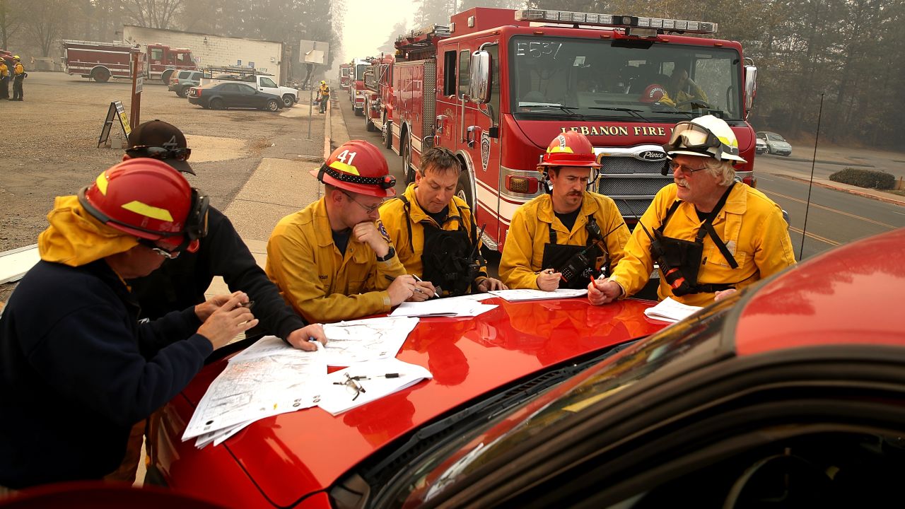 Firefighters hold a morning meeting as they battle the Camp Fire on Saturday in Paradise.