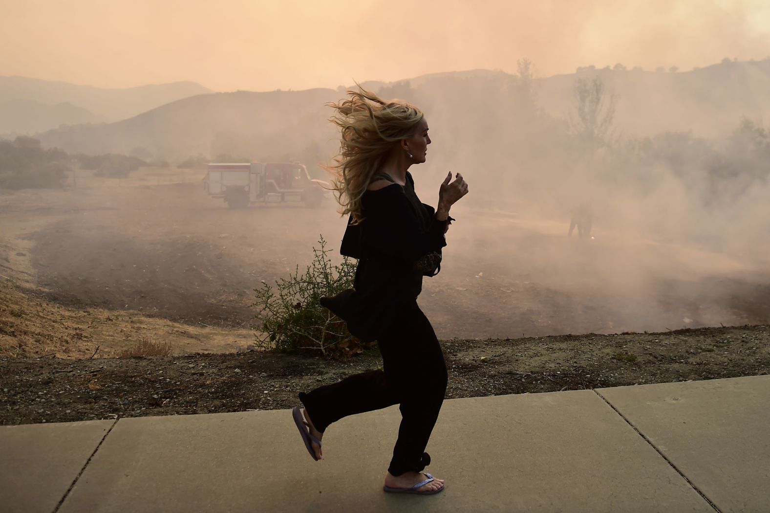 A woman runs in Calabasas as firefighters work to control a flare-up from the Woolsey Fire on November 10.