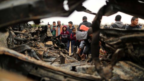People gather Monday around a vehicle destroyed in an Israeli air strike in Gaza.