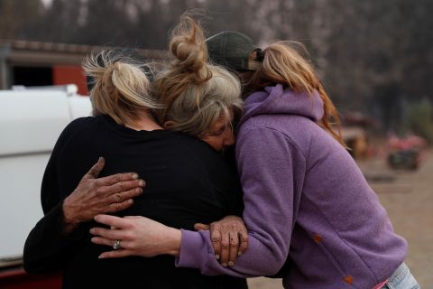 Cathy Fallon, who stayed behind in Paradise to tend to her horses during the Camp Fire, embraces Shawna De Long, left, and April Smith, right, who brought supplies for the horses.