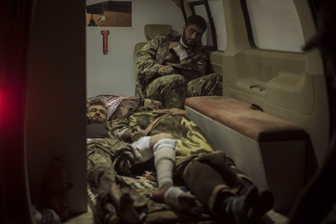 Two SDF soldiers await transfer to a hospital alongside the body of one their fallen comrades (bottom center) in an ambulance in Sousa, on October 25.