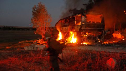 Israeli security forces and firefighters gather near the bus hit by fire from Gaza.