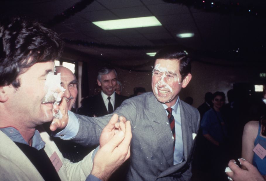Charles shares a playful pie in the face while visiting a community center in Manchester, England, in December 1983.
