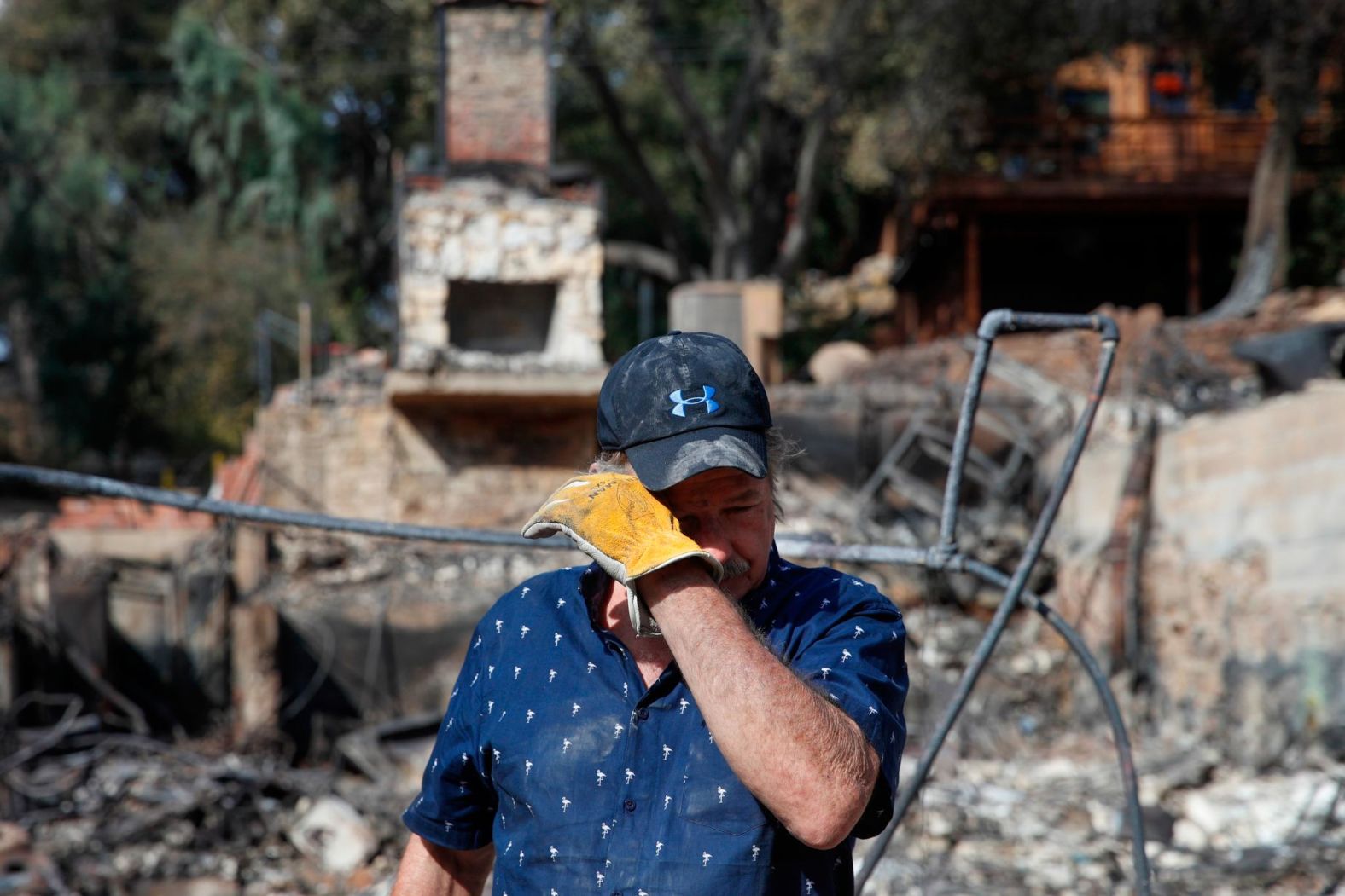 Roger Kelton wipes away tears on November 13 while searching through the remains of his mother-in-law's home in Agoura Hills. It was destroyed by the Woolsey Fire.