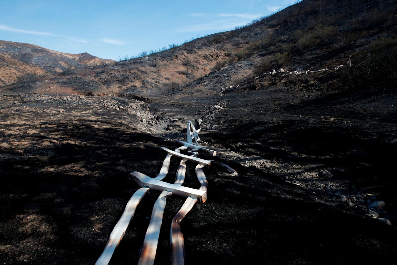 A melted fence runs along a hillside as firefighters battle the Woolsey Fire in Agoura Hills on November 13.