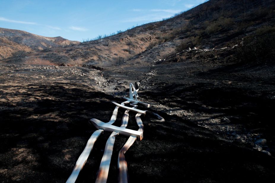 A melted fence runs along a hillside as firefighters battle the Woolsey Fire in Agoura Hills on November 13. 