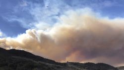 An airplane flies over a large wildfire plume from a recent flareup of the Woolsey Fire near Lake Sherwood, Calif., Tuesday, Nov. 13, 2018. Forecasters had warned of continuing fire danger in Southern California due to persistent Santa Ana winds, the withering, dry gusts that sweep out of the interior toward the coast, pushing back moist ocean breezes.  (AP Photo/Amanda Myers)