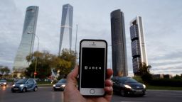 MADRID, SPAIN - OCTOBER 14:  In this Photo Illustration a smart phone displays a picture with the logo of the news taxi app 'Uber' near the Cuatro Torres 'Four Towers' business area on October 14, 2014 in Madrid, Spain. 'Uber' application started to operate in Madrid last September despite Taxi drivers claim it is an illegal activity and its drivers currently operate without a license. 'Uber' is an American based company which is quickly expanding to some of the main cities from around the world. 