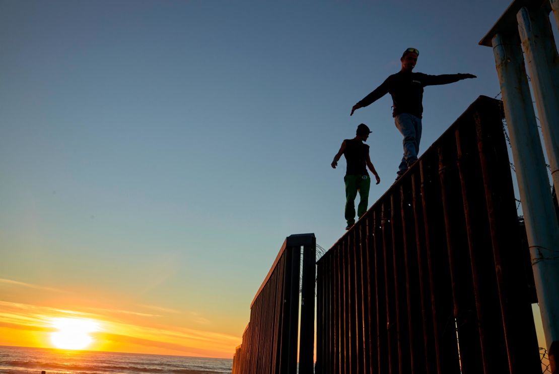 Two Central American migrants walk along the top of the border structure separating Mexico and the United States on Wednesday in Tijuana.
