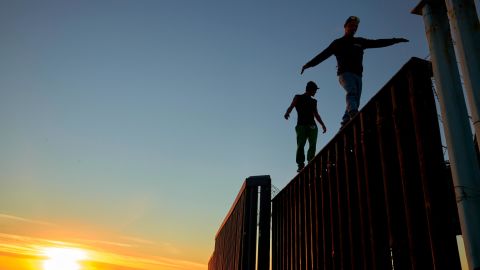 Two Central American migrants walk along the top of the border structure separating Mexico and the United States on Wednesday in Tijuana.