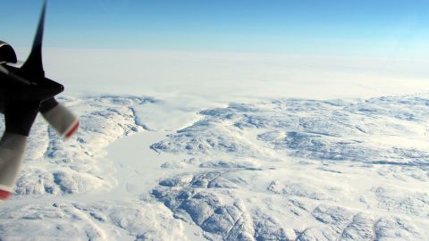 The Hiawatha impact crater is covered by the Greenland Ice Sheet, which flows just beyond the crater rim, forming a semi-circular edge. Part of this edge, seen in the top of the photograph, and a tongue of ice that breaches the crater's rim are shown in this photo taken during a NASA flight in April.