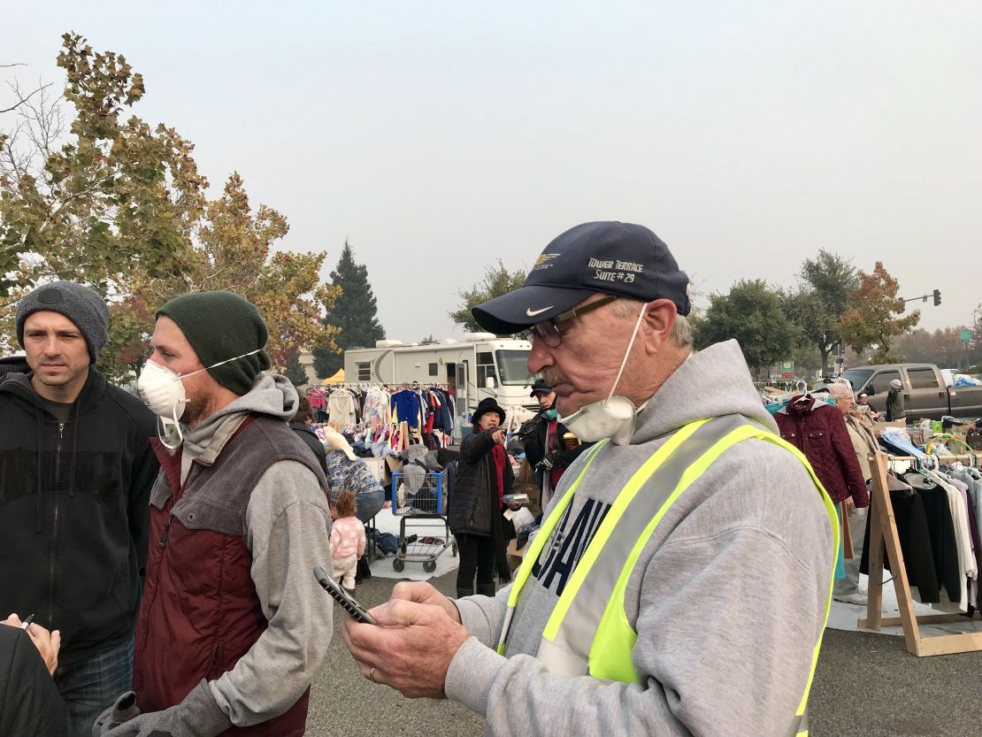 Rob Busick, left, wearing a mask, and Guido Barbero, right, checking his phone, help organize volunteer efforts.