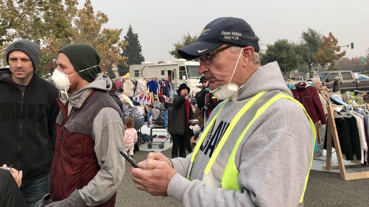 Rob Busick, left, wearing a mask, and Guido Barbero, right, checking his phone, help organize volunteer efforts.