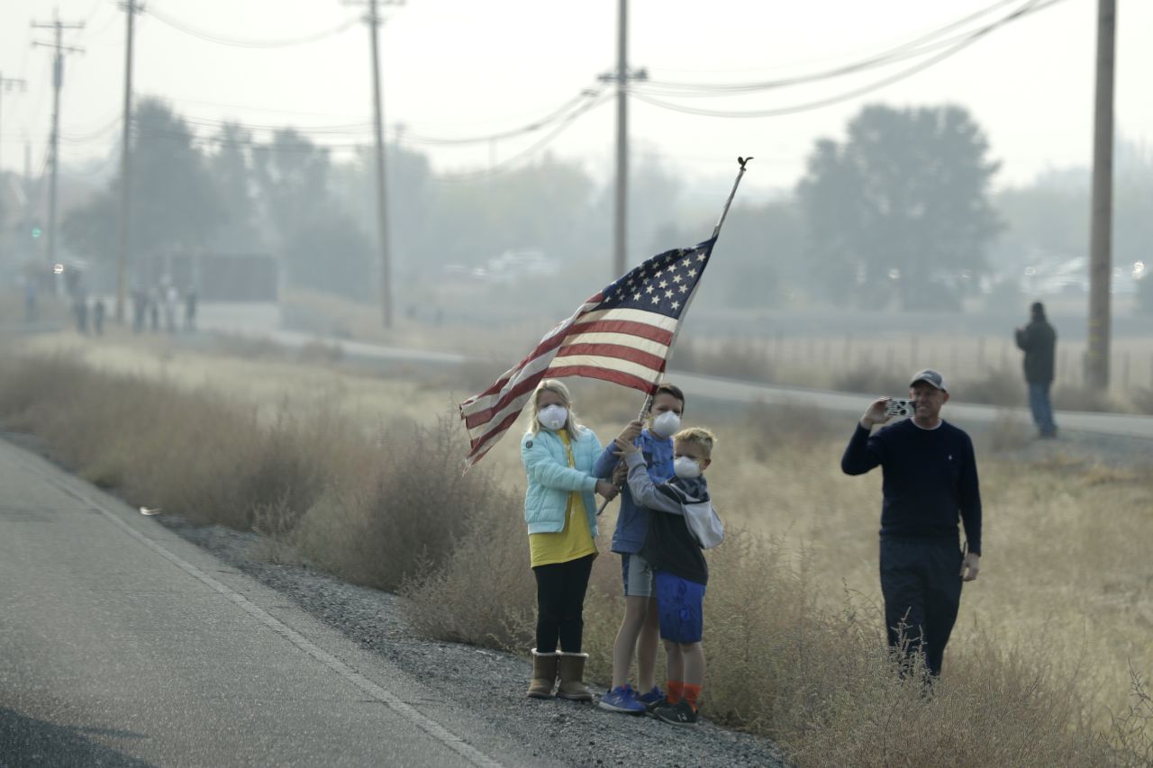 A group of children hold an American flag as the motorcade of President Donald Trump drives through Chico, California, on November 17.