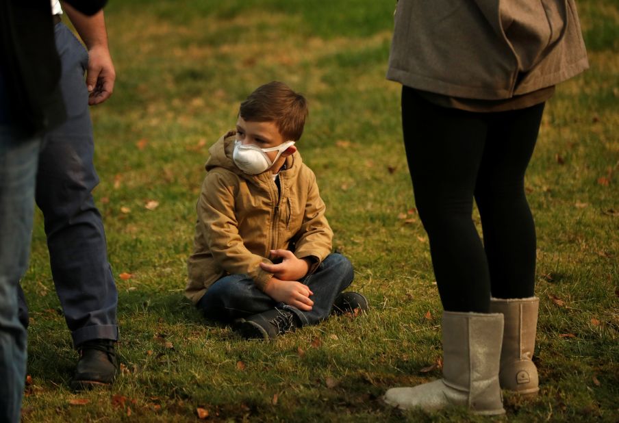 A child wears a smoke mask while watching President Trump''s motorcade in Chico on November 17.