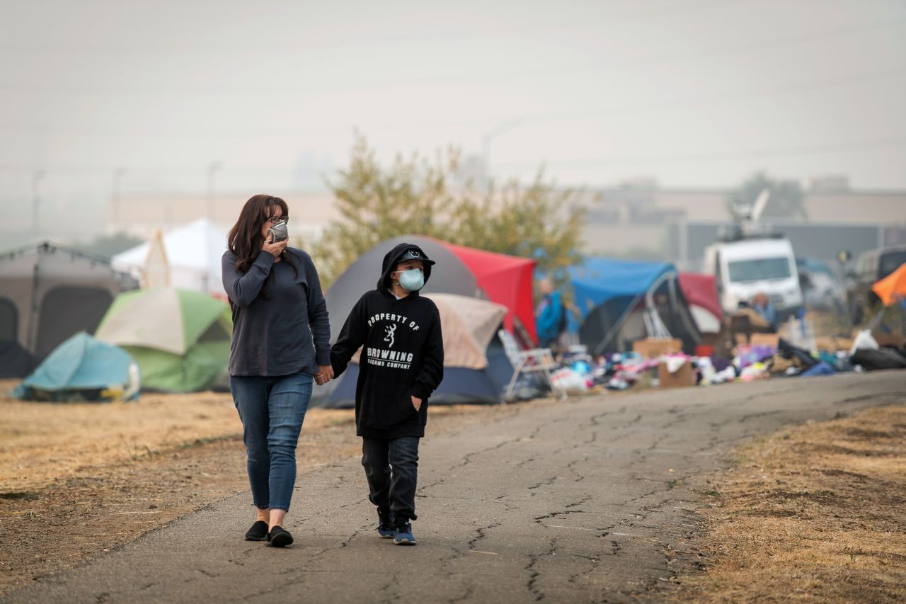 Evacuees wear disposable face masks as they walk through the tent city on November 15.