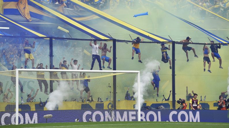 Fans of Boca Juniors scale a fence during a match between Boca Juniors and River Plate at the Estadio Alberto J. Armando on November 11 in Buenos Aires, Argentina. The match was scheduled be played on November 10, but was rescheduled because of heavy storms in Buenos Aires.