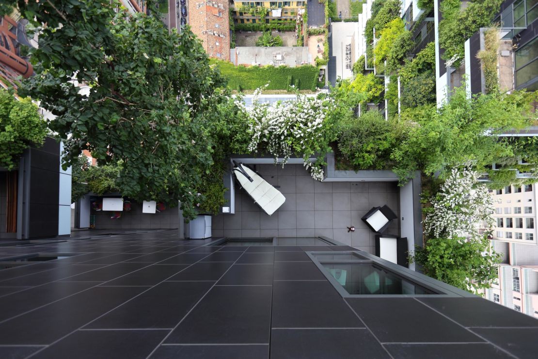 Greenery is placed on balconies across the two buildings' facades.